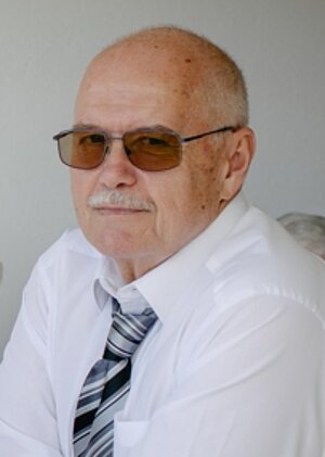 Ein Poritrait von einem Mann mit Sonnenbrille und Hemd + Krawatte.