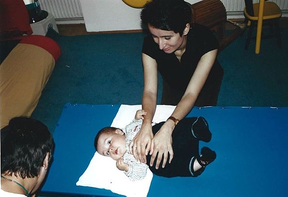 Frau massiert Kleinkind auf blauer Matte den Bauch