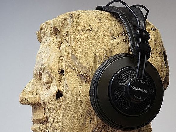aus Holz geschnitzter Kopf im Seitenprofil fotografiert mit Kopfhörern auf