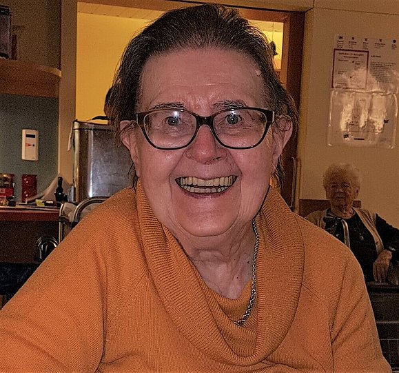 Portrait einer herzlich lachenden, älteren Dame mit Brille.