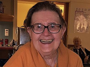 Portrait einer herzlich lachenden, älteren Dame mit Brille.