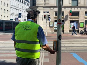Mann steht an Straße mit Warnweste Aufschrift Wir geben Sicherheit