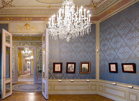 Barocker Raum mit Kronleuchter und Gemälden auf blauer Tapete