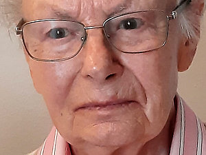 Ältere Dame mit weißen, kurzen Haaren, Brille und hellrosa Hemd.