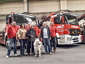 Eine Gruppe von Personen und ein Blindenhunde stehen vor Lastkraftwagen