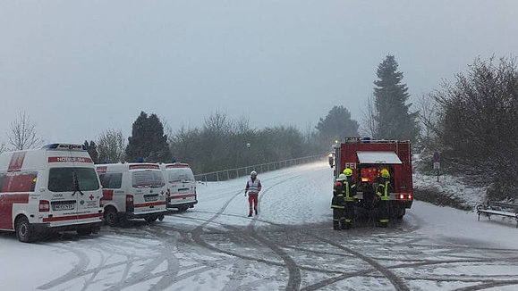 Ein Feuerwehrauto und drei Krankenwagen parken auf schneeigem Boden