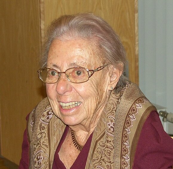 Portrait einer älteren Dame mit Brille die herzlich lacht