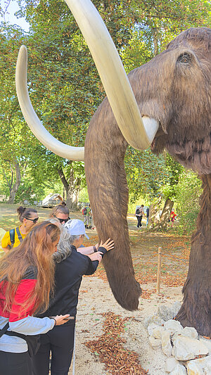 Der Rüssel einer Mammut-Attrapppe wird von einer blinden Frau ertastet