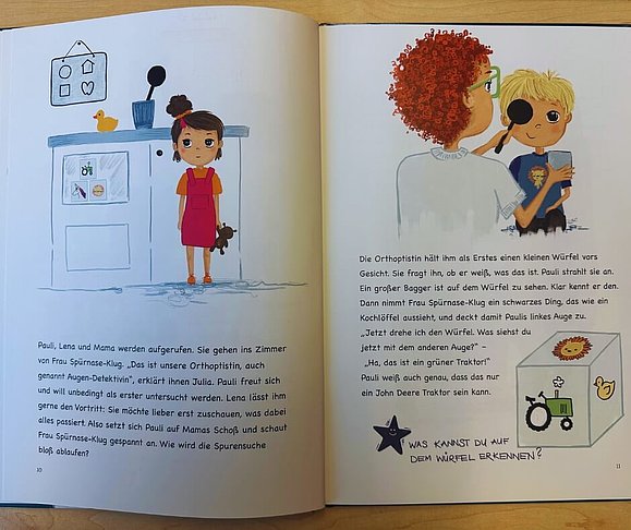 aufgeschlagenes Bilderbuch mit Text und Grafik: links Kind vor dem Küchenschrank und rechts Augenärztin hält Lupe zum Auge von Kind mit blonden kurzen Haaren