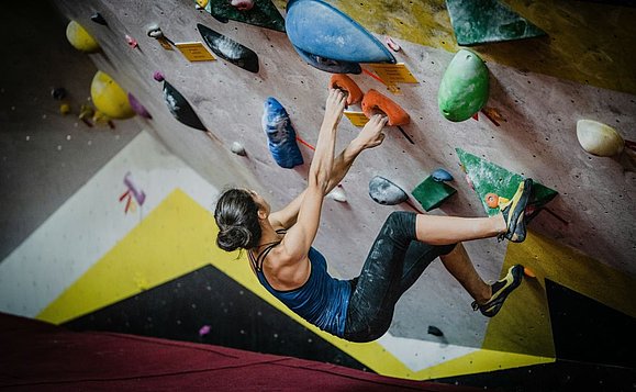 Kennenlernen der Faszination Klettern unter professioneller Anleitung. Foto: Unsplash. Frau klettert in Halle