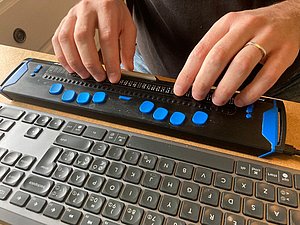 Hände bedienen eine Braillezeile.