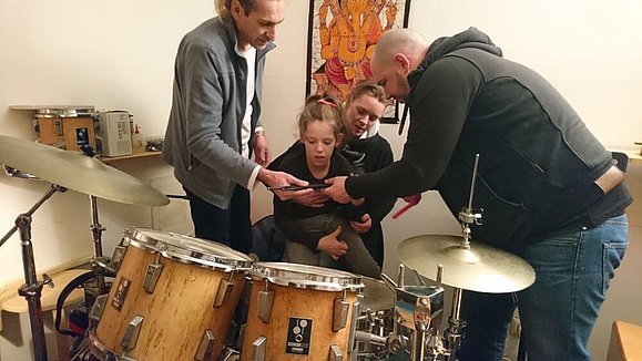 Drei Erwachsene und ein Kind sind um das Schlagzeug versammelt