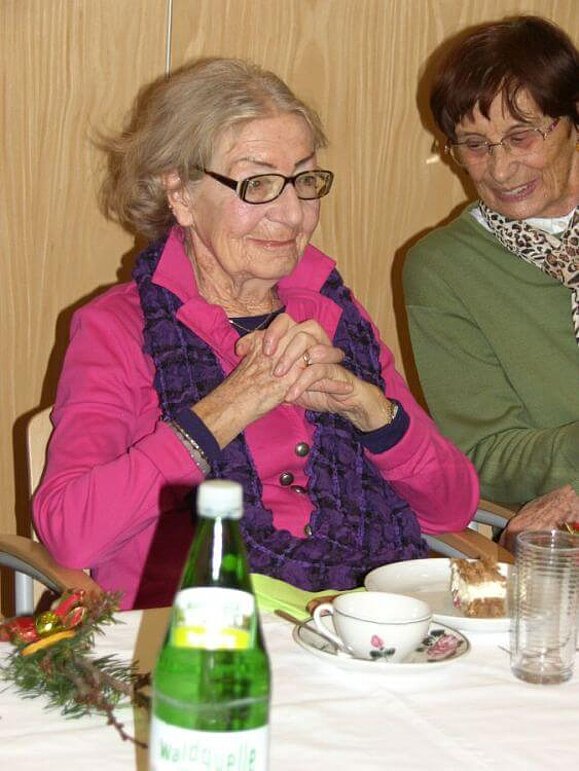 Zwei Damen sitzen mit Kuchen und Kaffee bei einem Tisch