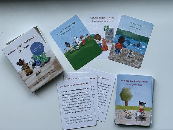 Mehrere Affirmationskarten mi Illustrationen von fröhlichen Kindern und Verpackung