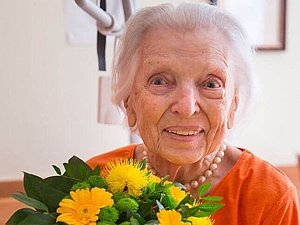 Portrait Lygia Kapraleck mit oranger Bluse und gelben Blumen, Copyright: F. Pfluegl.