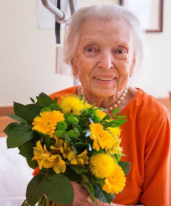 Portrait Lygia Kapraleck mit oranger Bluse und gelben Blumen, Copyright: F. Pfluegl.