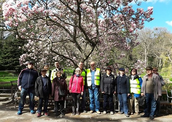 Eine Gruppe von 13 Personen steht im Park vor einem blühendem Baum.