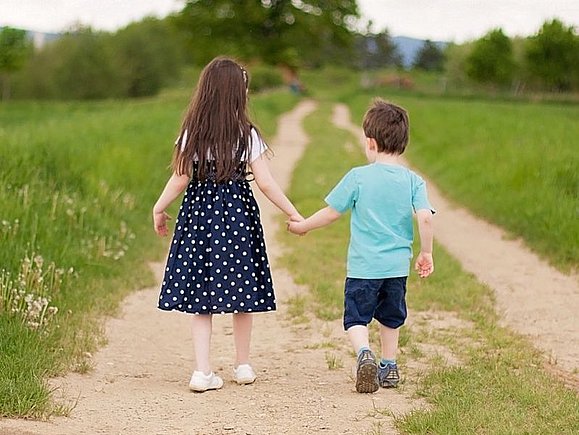 Sehsternchen Lisa und Bruder Emil gehen Hand in Hand einen Feldweg entlang.