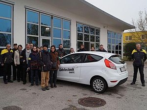 Eine Gruppe von Sehschwachen und Blinden steht neben einem Auto der Fahrtechnik ÖAMTC