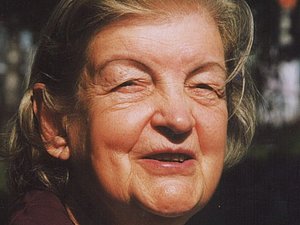 Ältere Frau mit Kinnlangen Haaren lächelt in die Ferne