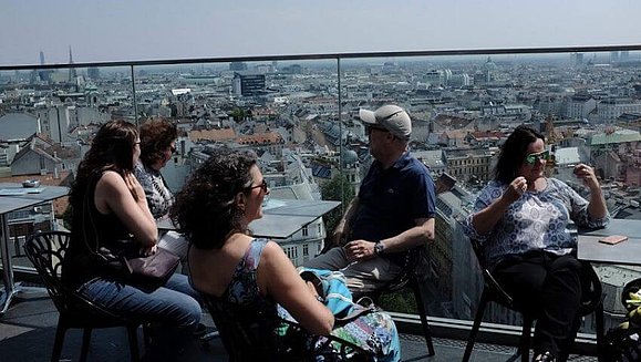 5 Mitarbeiter sitzen im Dachcafé und blicken über die Dächer von Wien.