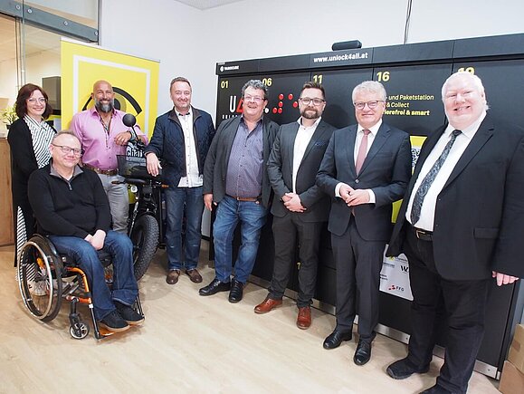 Gruppenfoto mit versammelten Personen vor Paketbox lächeln in die Kamera