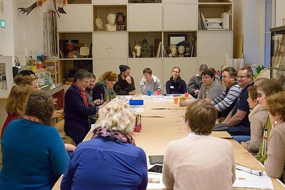 Blick in eine Workshop-Gruppe mit zahlreichen Teilnehmenden an einem großen Tisch