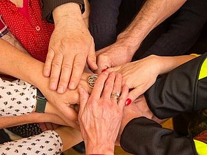 Mehrere Hände treffen sich in der Mitte und liegen übereinander.