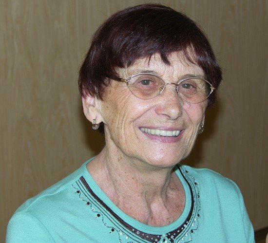 Eine ältere Frau mit Brille lächelt in die Kamera 