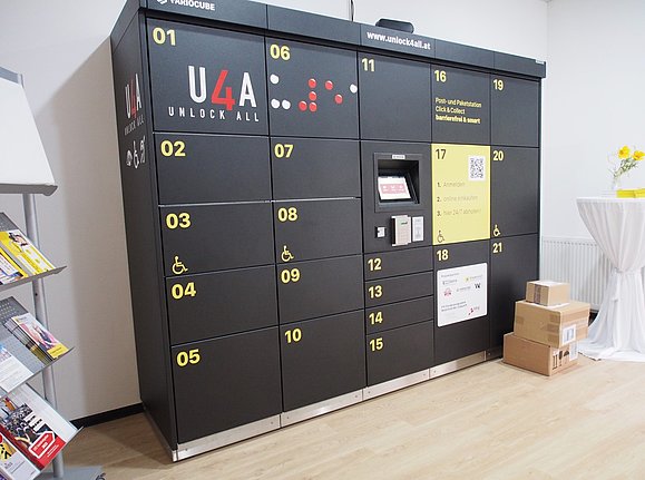 Moderne Paketbox in schwarz mit kontrastreicher gelber Aufschrift mit Monitor in einem Raum