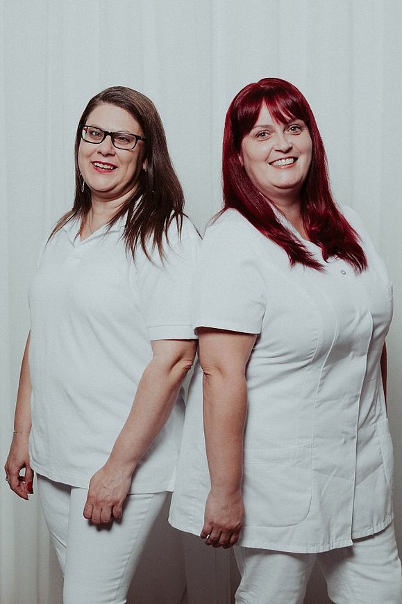 Zwei Frauen von discovering hands mit weißer Pflegerinnenkleidung lächeln in die Kamera