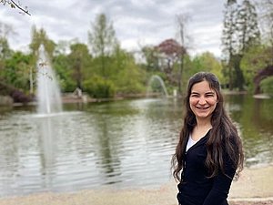 Junge Frau im Park lacht in die Kamera