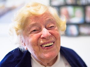 Ältere Frau mit gelben Haaren lacht in die Kamera