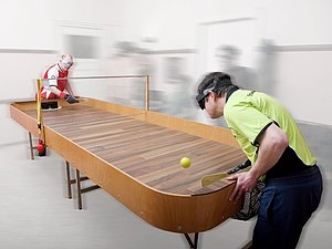 Showdown-Tisch und zwei Spieler mit Augenbinden, Handschuhen und Schlägern ausgestattet, spielen den Ball.