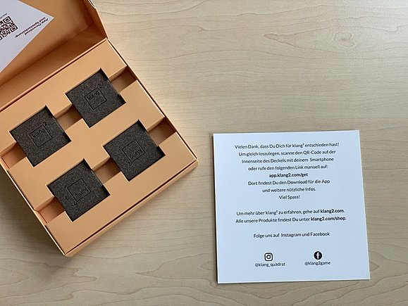 Orangefarbene geöffnete Kiste mit eingepflegten Memorykarten und Spielebeschreibung rechts