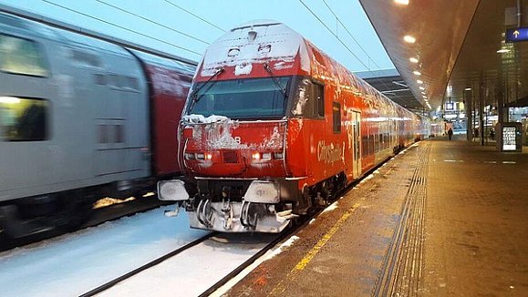 Roter Zug der ÖBB mit Schnee bedeckt, steht am Bahnhof. 