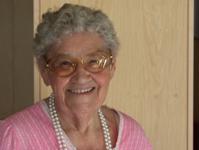 Eine ältere Dame mit Brillen lächelt fröhlich in die Kamera 