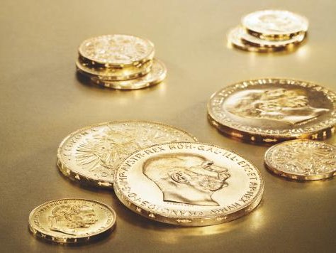 Verschiedene Goldmünzen auf goldenem Untergrund.