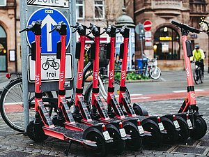 mehrere rote E-Scooter mit Aufschrift "VOI" ordentlich nebeneinandergeparkt