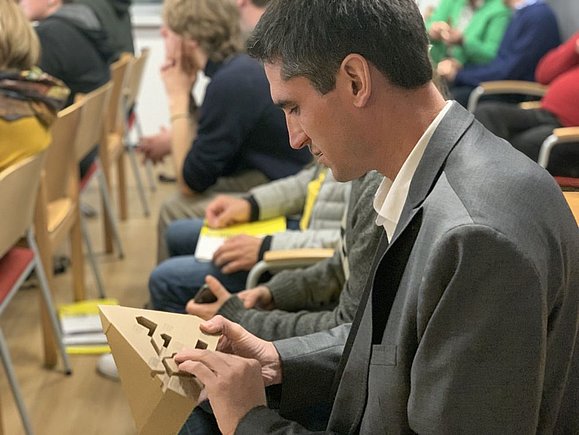 Mann mit Anzug tastet Holz-Pyramide