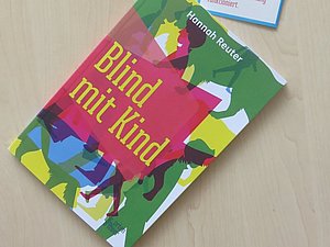 Das Buch "Blind mit Kind" liegt auf einem Flyer mit Zitaten aus dem Buch.
