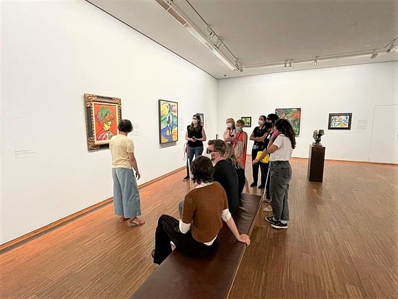 Menschengruppe teils mit Langstock vor Gemälden im Museum