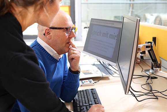 Mann und Frau schauen beide auf Bildschirm mit vergrößerter Schrift