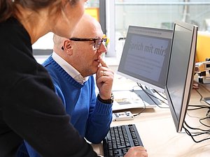 Mann und Frau schauen beide auf Bildschirm mit vergrößerter Schrift