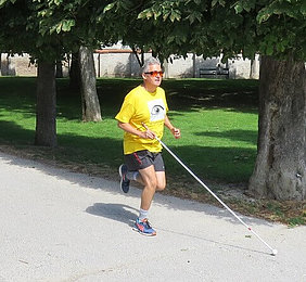 Harald läuft mit einem Langstock nach US-Norm in einem Park.