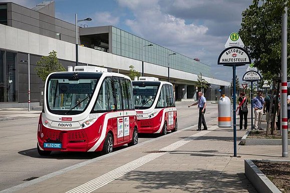 Haltestelle mit zwei rot-weißen E-Bussen