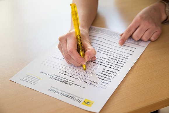 Wir unterstützen Sie bei Anträgen. Copyright Foto: Franz Pfluegl Es füllt jemand ein Formular aus.