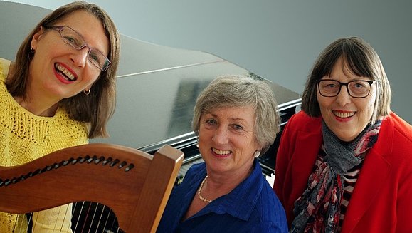 drei Frauen mit Harfe lächeln in die Kamera