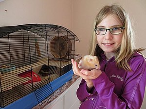 Julia hat ihren Hamster auf dem Arm und strahlt.