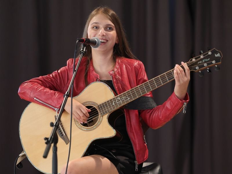 Eine junge Frau mit dunklen langen Haaren mit einer Gitarre in der Hand